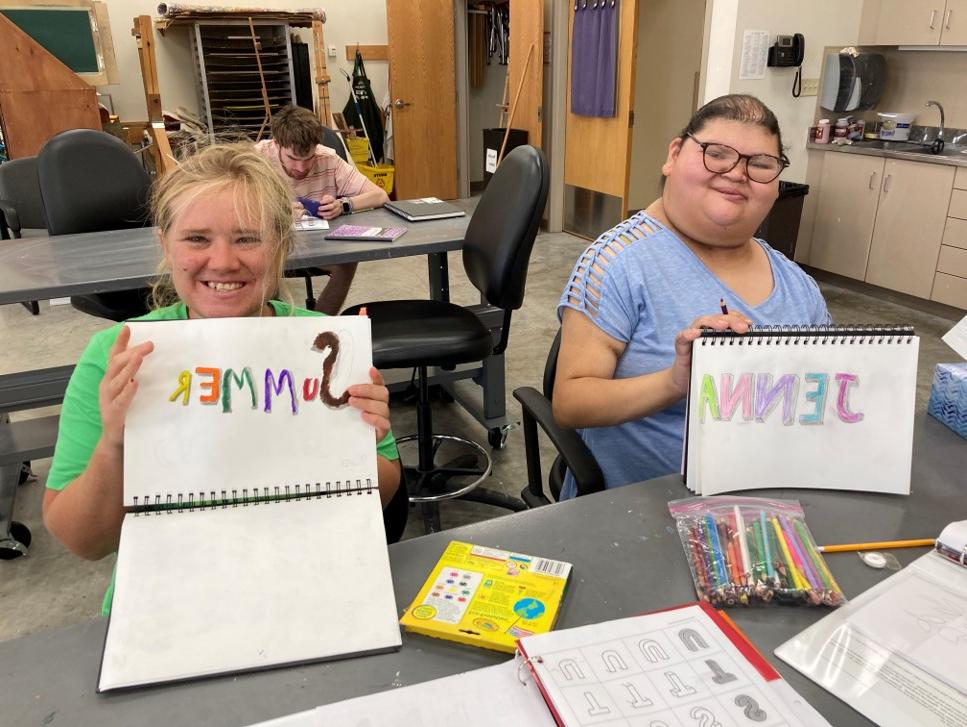 Two CFL students drawing their names, Jenna and Summer, in art class